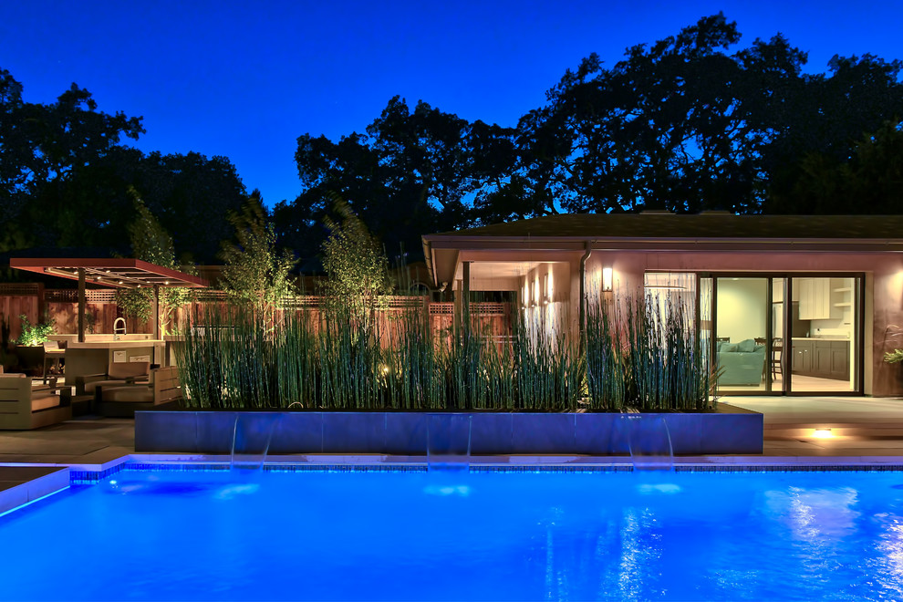 Ejemplo de piscina con fuente contemporánea grande rectangular en patio trasero con suelo de baldosas