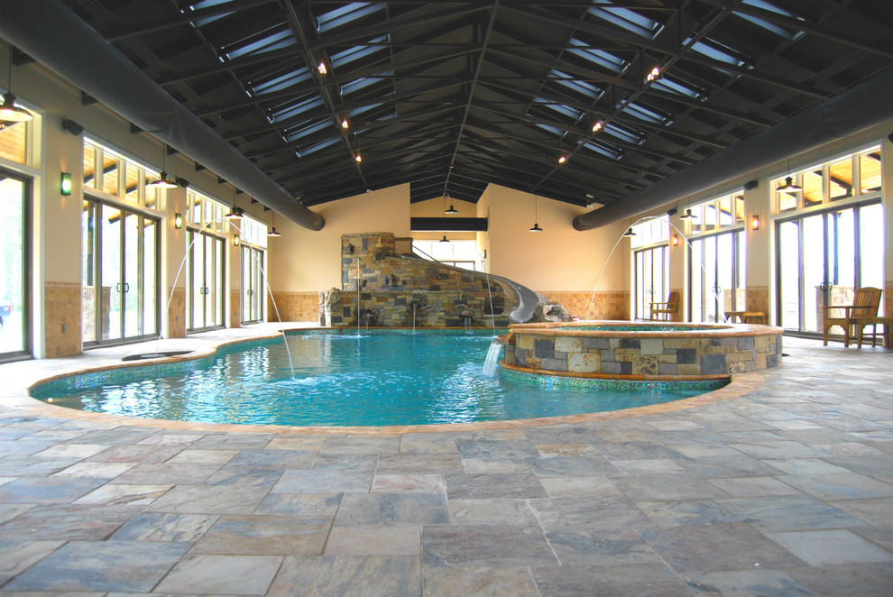 Bild på en mycket stor funkis inomhus, anpassad pool, med vattenrutschkana och naturstensplattor