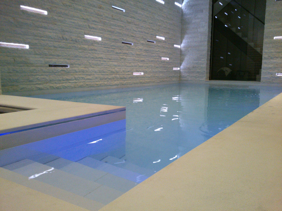 Foto de piscina con fuente contemporánea de tamaño medio en forma de L y interior con adoquines de piedra natural