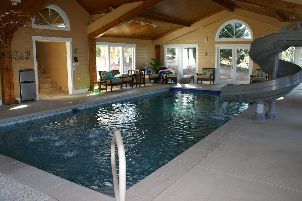 Ejemplo de piscina con tobogán alargada costera de tamaño medio rectangular y interior con losas de hormigón