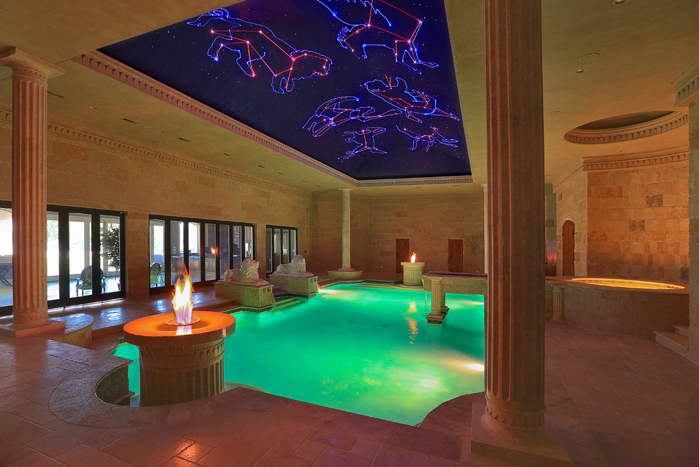 Cette image montre une grande piscine intérieure méditerranéenne rectangle avec des pavés en pierre naturelle.