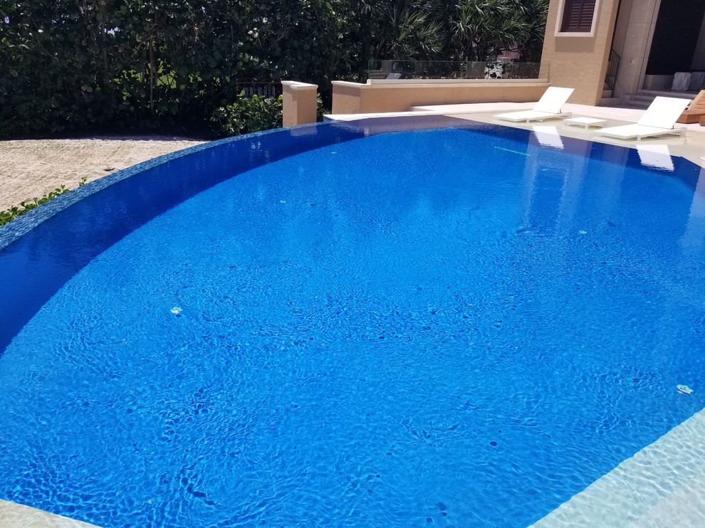 Идея дизайна: большой бассейн-инфинити произвольной формы на заднем дворе в средиземноморском стиле с фонтаном и покрытием из каменной брусчатки