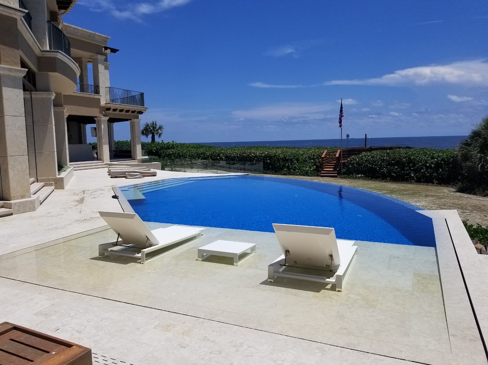 Diseño de piscina con fuente infinita mediterránea grande a medida en patio trasero con adoquines de piedra natural