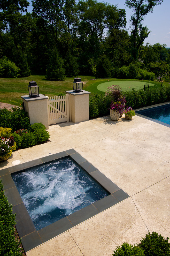 Diseño de piscina con fuente infinita contemporánea grande rectangular en patio trasero con suelo de hormigón estampado