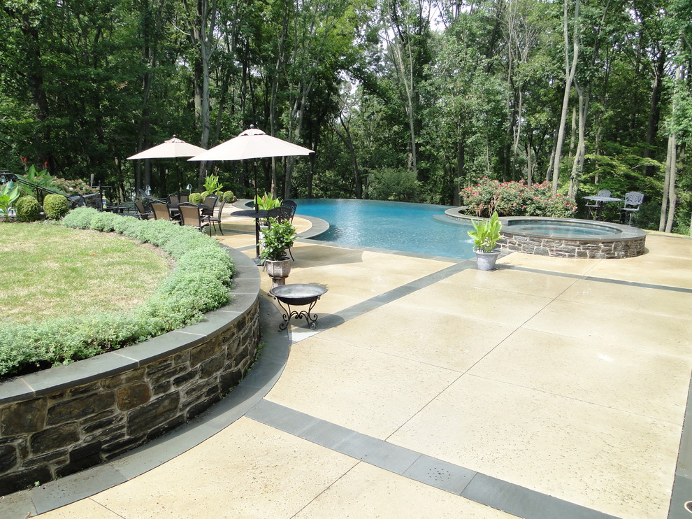 Cette image montre une grande piscine à débordement et arrière design sur mesure avec un point d'eau et une dalle de béton.