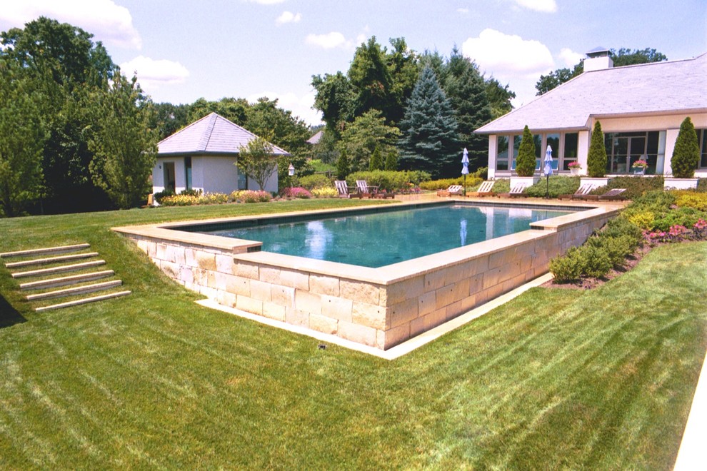 Idee per una grande piscina a sfioro infinito classica rettangolare dietro casa con pavimentazioni in pietra naturale e una vasca idromassaggio
