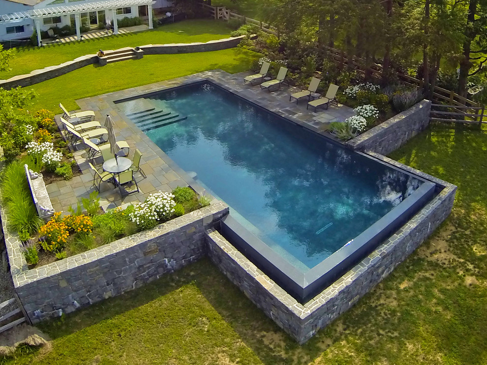 Imagen de piscina infinita tradicional grande rectangular en patio trasero con adoquines de piedra natural