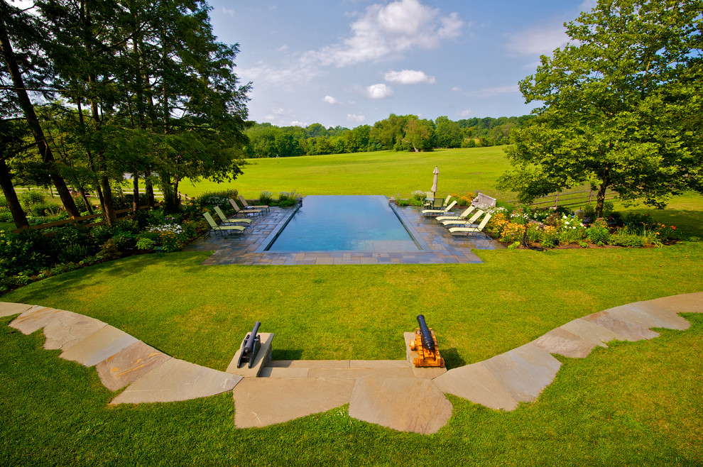Пример оригинального дизайна: большой прямоугольный бассейн-инфинити на заднем дворе в классическом стиле с фонтаном и покрытием из каменной брусчатки
