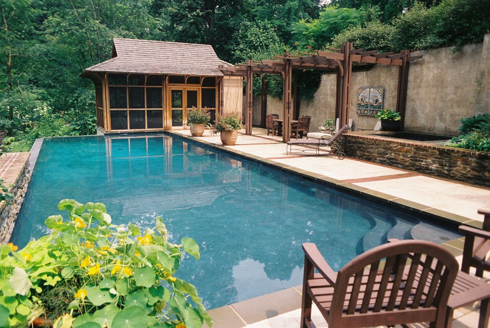 Ispirazione per una piscina a sfioro infinito contemporanea rettangolare di medie dimensioni e dietro casa con pavimentazioni in pietra naturale e una vasca idromassaggio