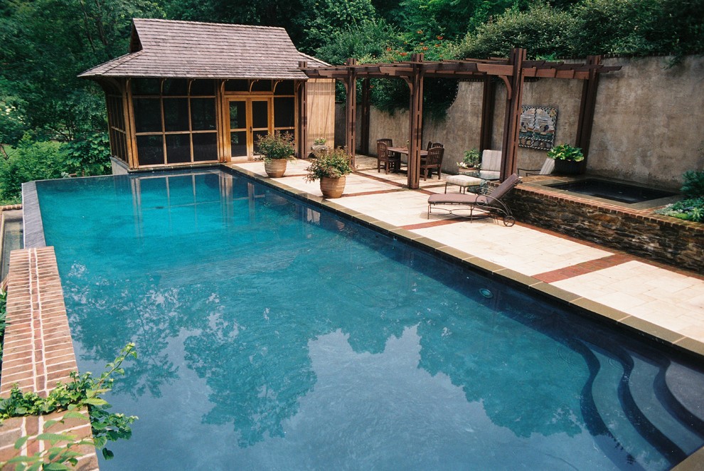 На фото: прямоугольный бассейн-инфинити среднего размера на заднем дворе в современном стиле с покрытием из каменной брусчатки и джакузи