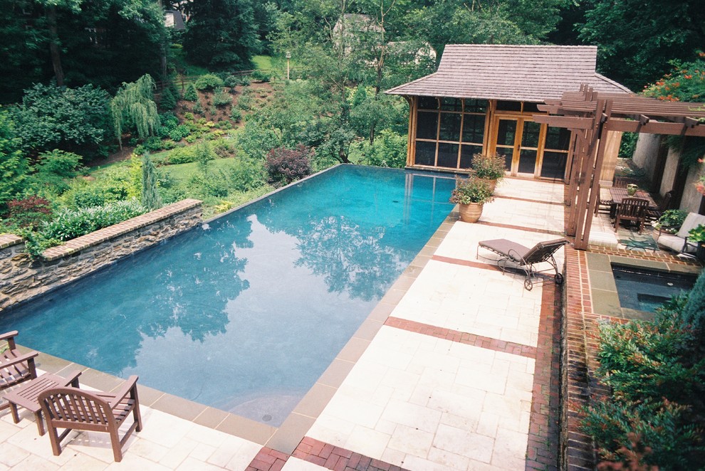 Idées déco pour une piscine à débordement et arrière classique de taille moyenne et rectangle avec des pavés en pierre naturelle et un bain bouillonnant.
