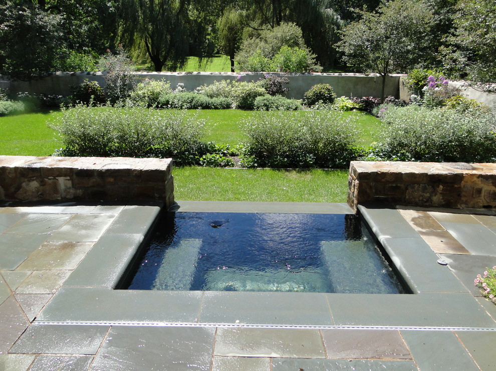 Small elegant courtyard stone and rectangular infinity hot tub photo in Philadelphia
