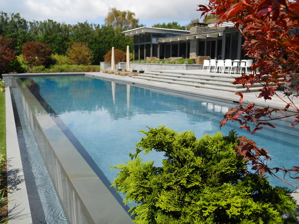Immagine di una piscina a sfioro infinito contemporanea con pavimentazioni in pietra naturale