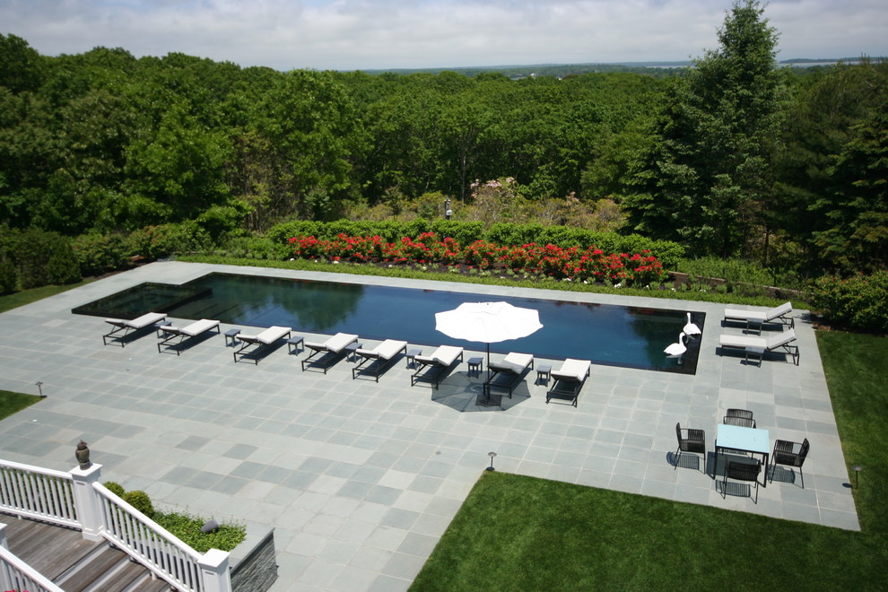 Idee per una piscina a sfioro infinito design rettangolare con una vasca idromassaggio e pavimentazioni in pietra naturale