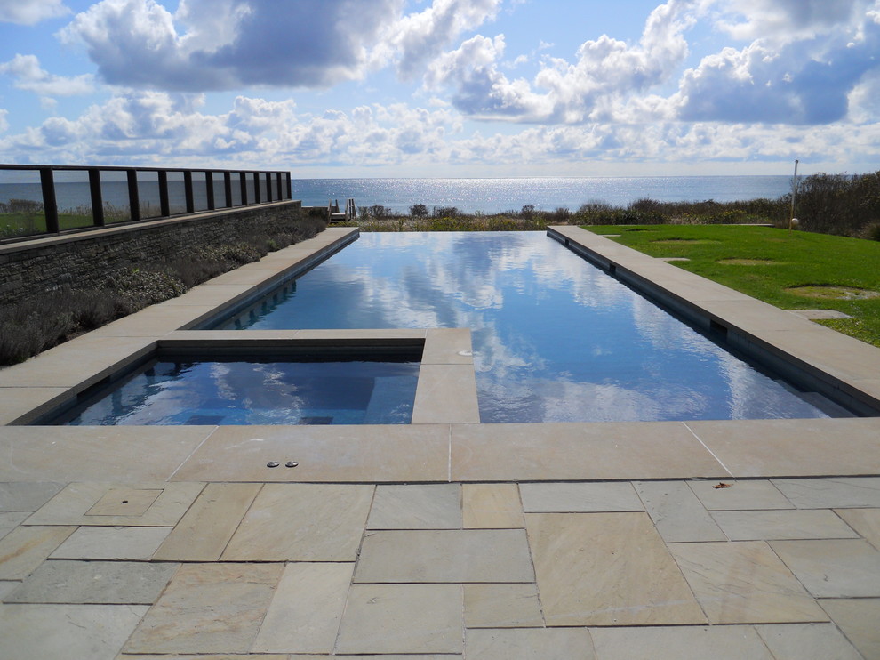 Imagen de piscinas y jacuzzis infinitos contemporáneos en patio trasero con adoquines de piedra natural