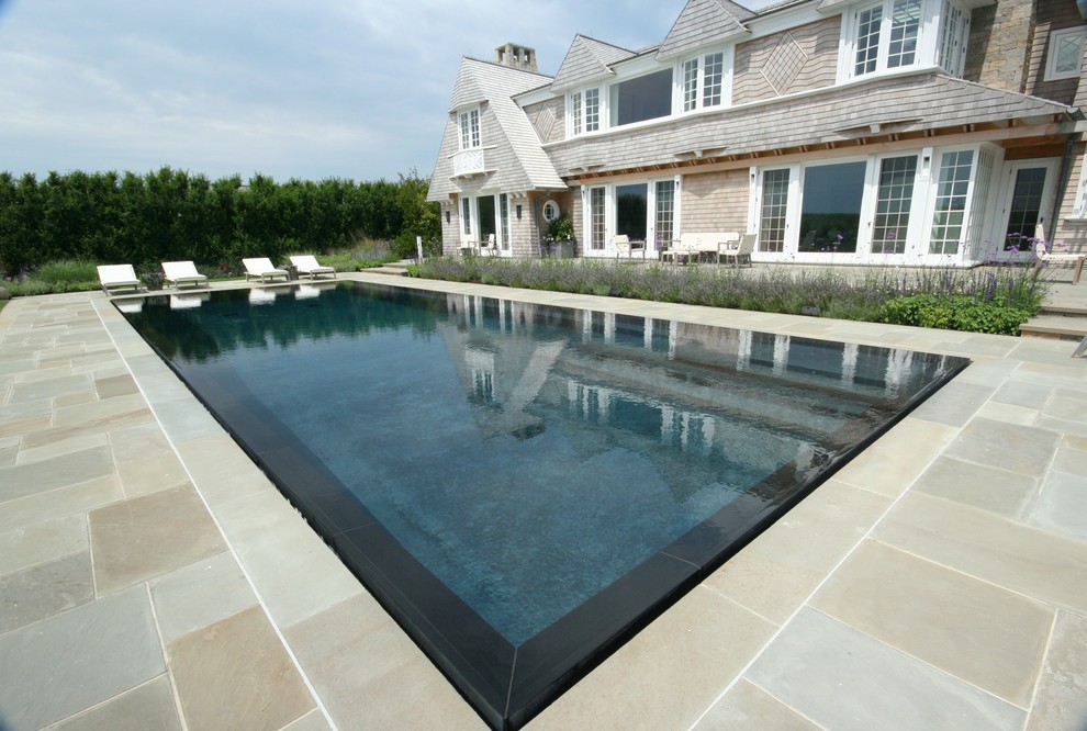 Foto di una piscina a sfioro infinito contemporanea rettangolare dietro casa con pavimentazioni in pietra naturale