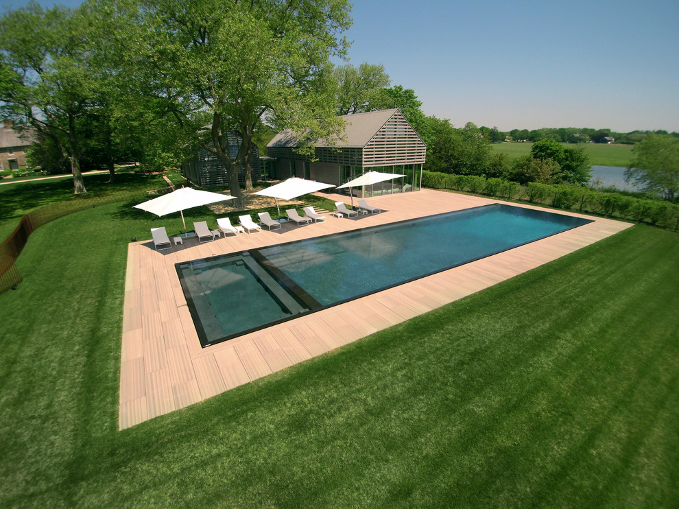Immagine di un'ampia piscina a sfioro infinito contemporanea rettangolare dietro casa con una vasca idromassaggio e pavimentazioni in cemento