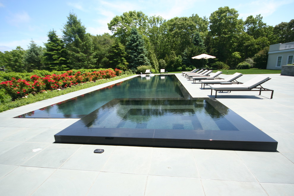 На фото: прямоугольный бассейн-инфинити в современном стиле с джакузи и покрытием из каменной брусчатки с