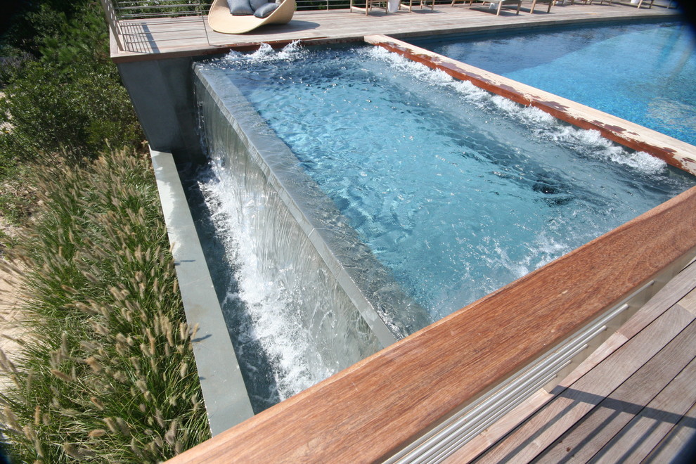 Idee per una piscina a sfioro infinito contemporanea rettangolare nel cortile laterale con una vasca idromassaggio e pedane