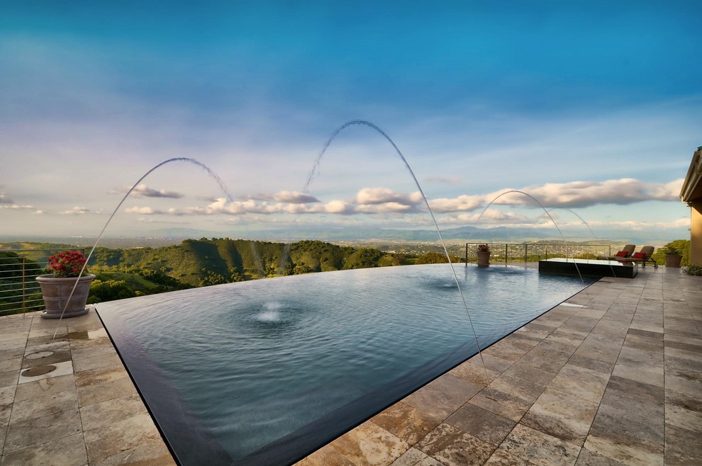 На фото: прямоугольный бассейн-инфинити среднего размера на заднем дворе в стиле модернизм с фонтаном и покрытием из каменной брусчатки