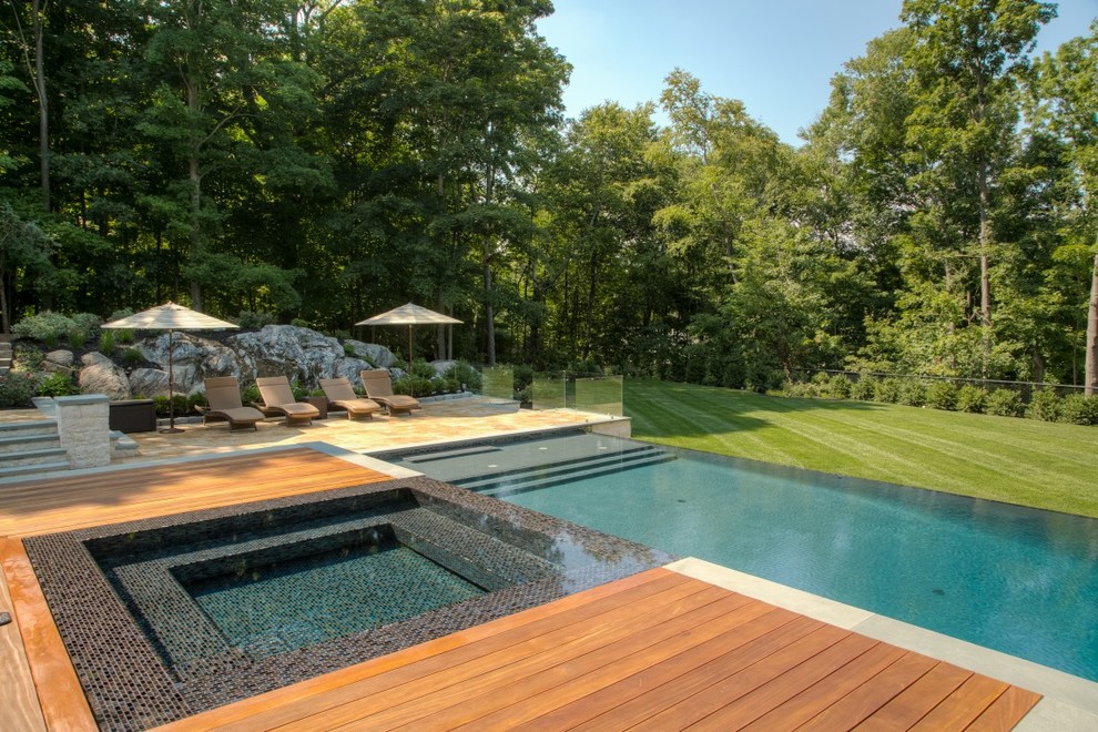 Großer Moderner Infinity-Pool hinter dem Haus in rechteckiger Form mit Wasserspiel und Natursteinplatten in New York