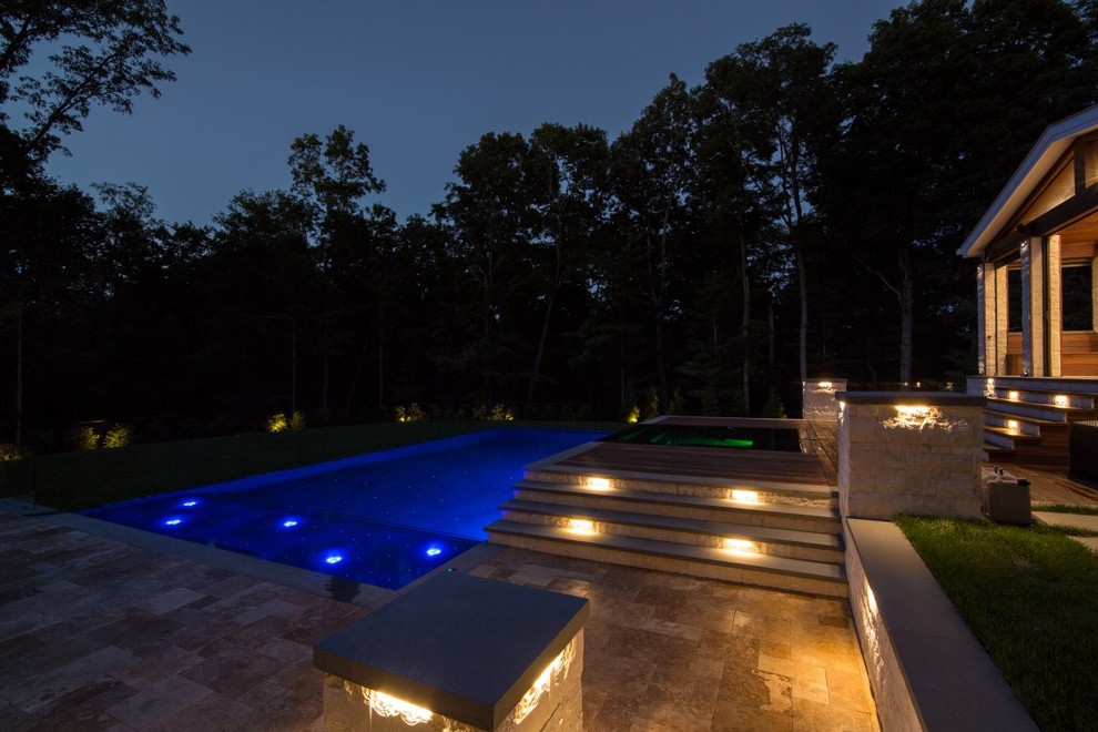 Esempio di una grande piscina a sfioro infinito minimalista rettangolare dietro casa con fontane e pavimentazioni in pietra naturale