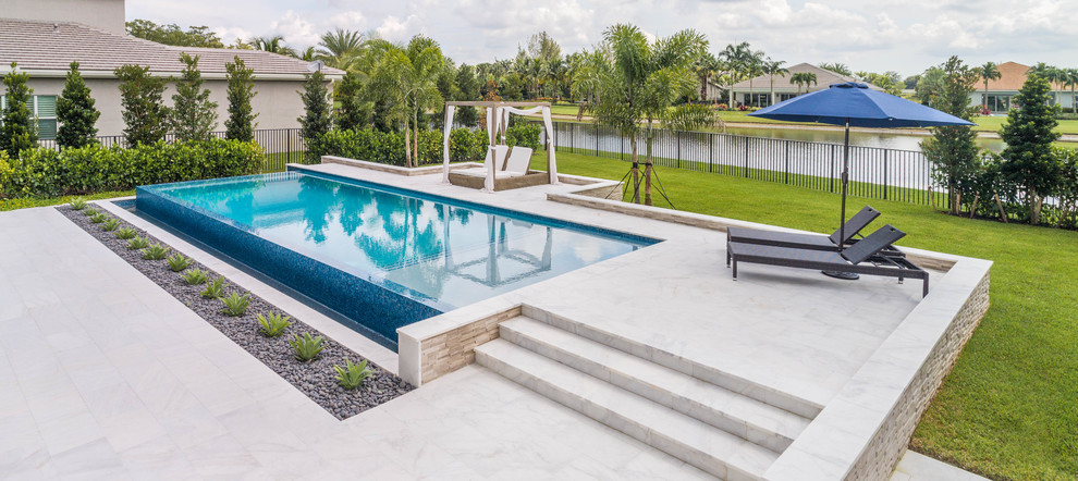 Immagine di una grande piscina a sfioro infinito moderna rettangolare dietro casa