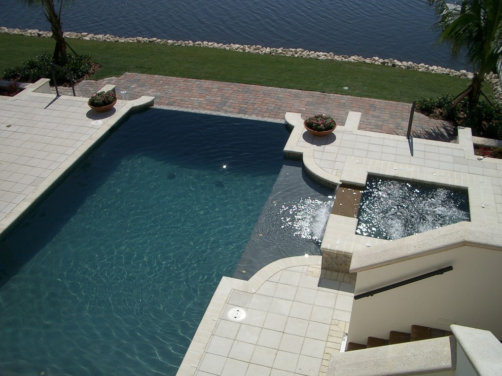 Foto di una grande piscina a sfioro infinito contemporanea rettangolare dietro casa con una vasca idromassaggio e pavimentazioni in cemento