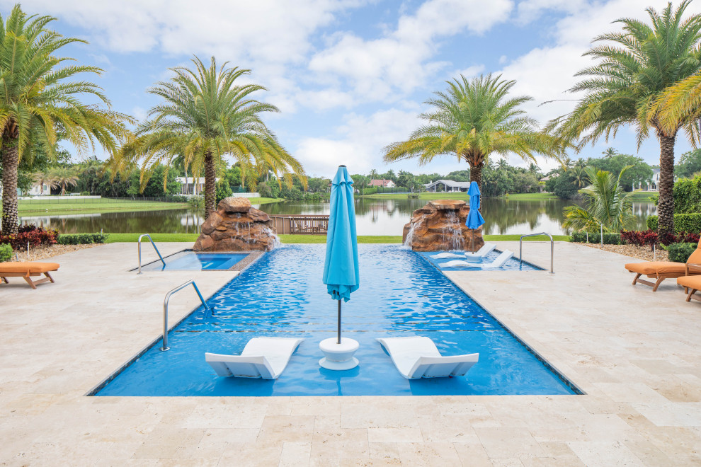 Großer Pool hinter dem Haus in rechteckiger Form mit Natursteinplatten in Miami