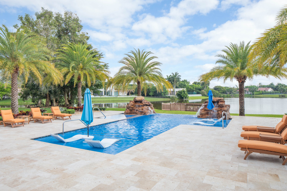 Diseño de piscinas y jacuzzis infinitos exóticos grandes rectangulares en patio trasero con adoquines de piedra natural