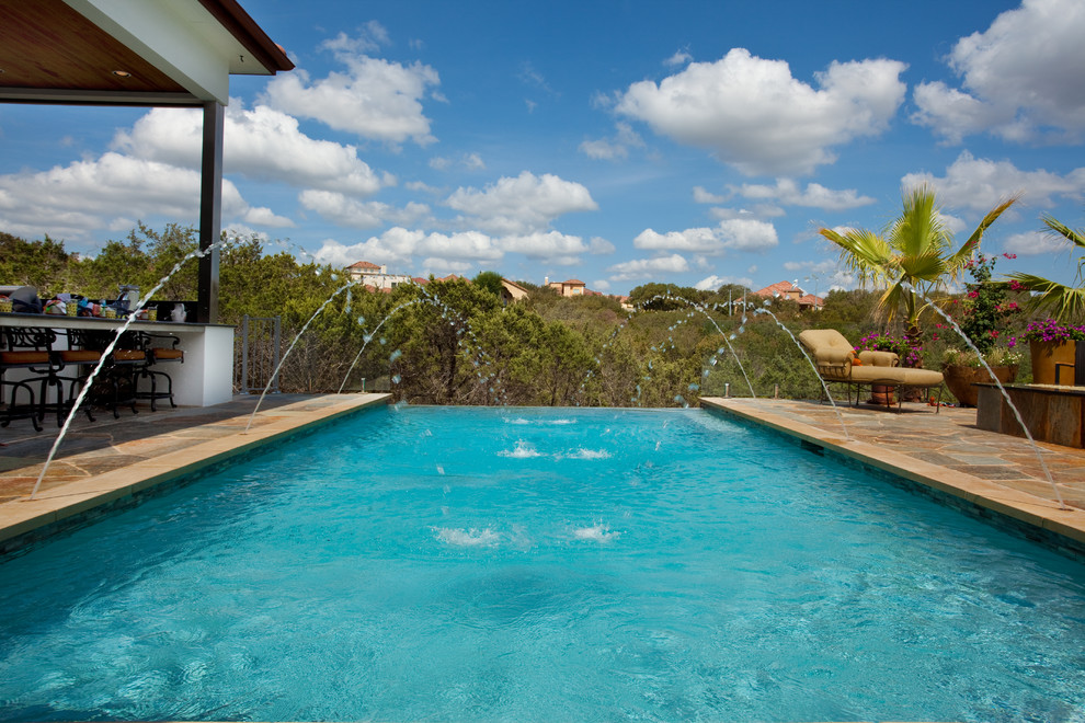 Example of a mid-sized mountain style backyard stone and rectangular infinity pool design in Austin