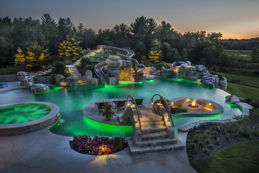 Idee per un'ampia piscina a sfioro infinito personalizzata dietro casa con un acquascivolo e pavimentazioni in pietra naturale