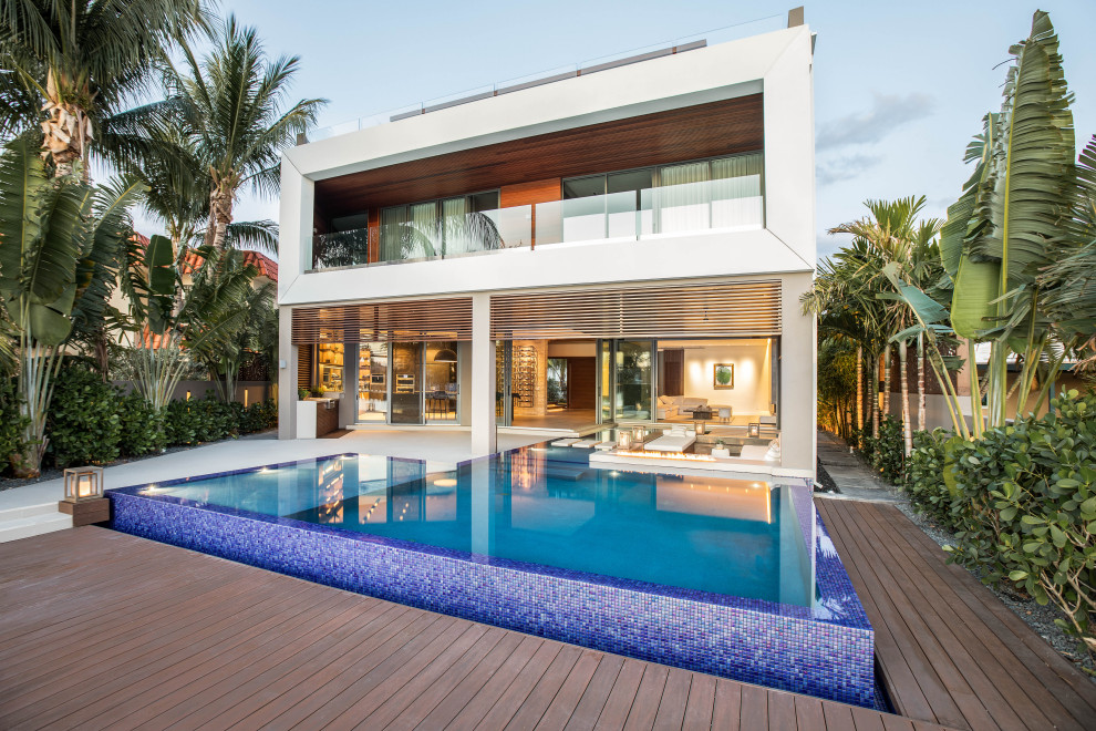 Pool - huge modern backyard custom-shaped infinity pool idea in Miami with decking