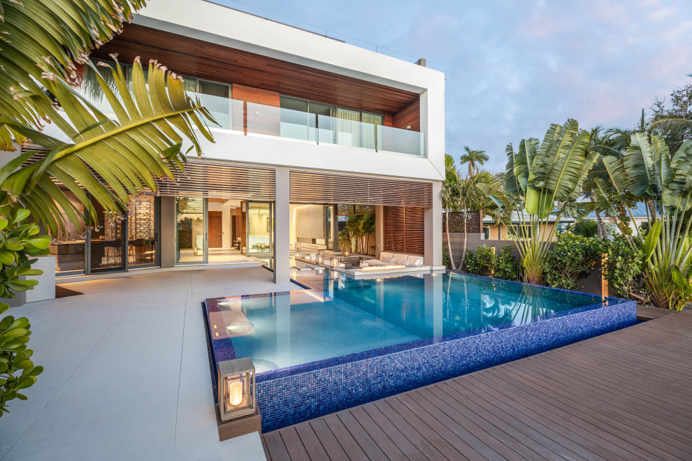 This is an example of an expansive modern back custom shaped infinity swimming pool in Miami with decking.