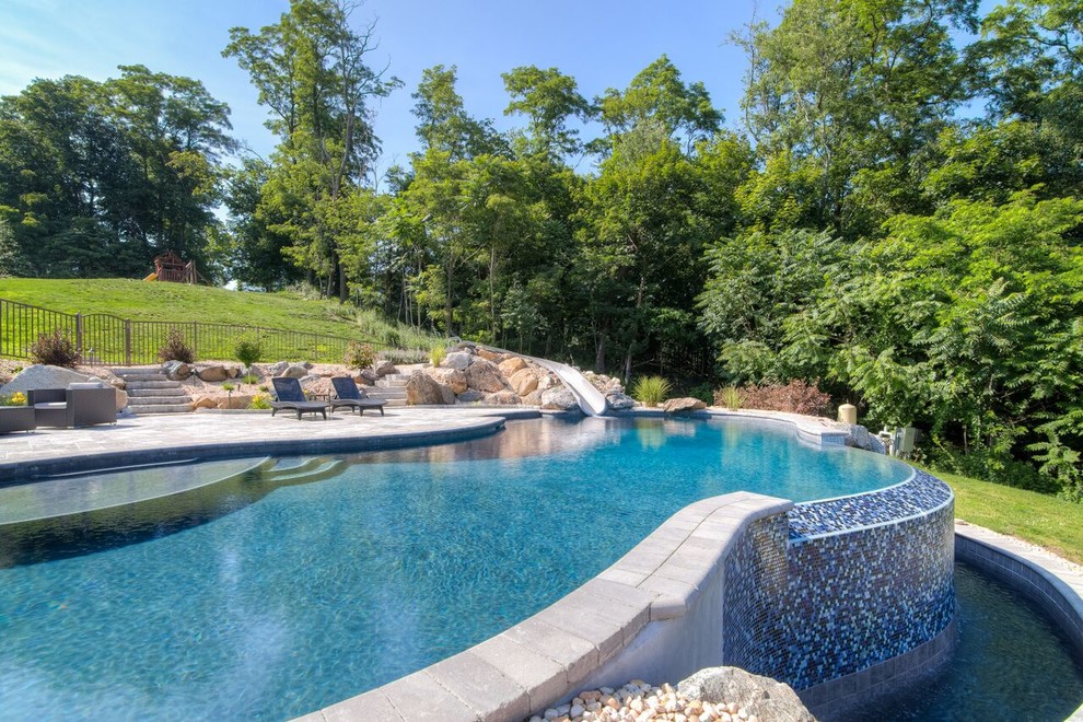 Esempio di una piscina a sfioro infinito minimal personalizzata dietro casa con un acquascivolo e pavimentazioni in pietra naturale