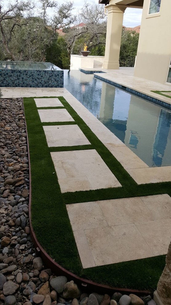 Foto di una grande piscina a sfioro infinito minimalista rettangolare dietro casa con una vasca idromassaggio e cemento stampato