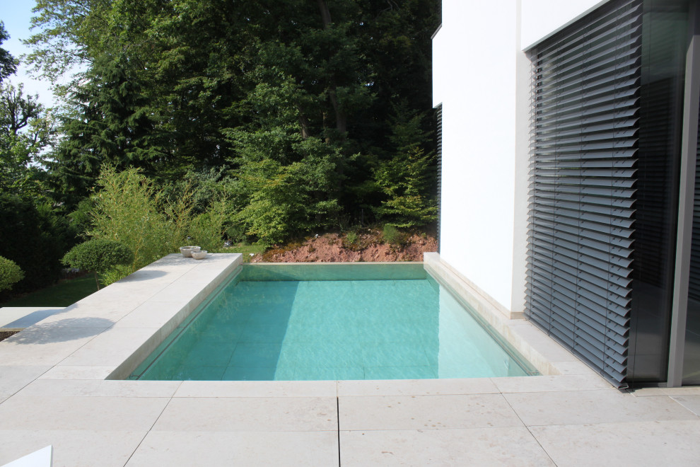 Mittelgroßer Mediterraner Infinity-Pool neben dem Haus mit Natursteinplatten in Frankfurt am Main