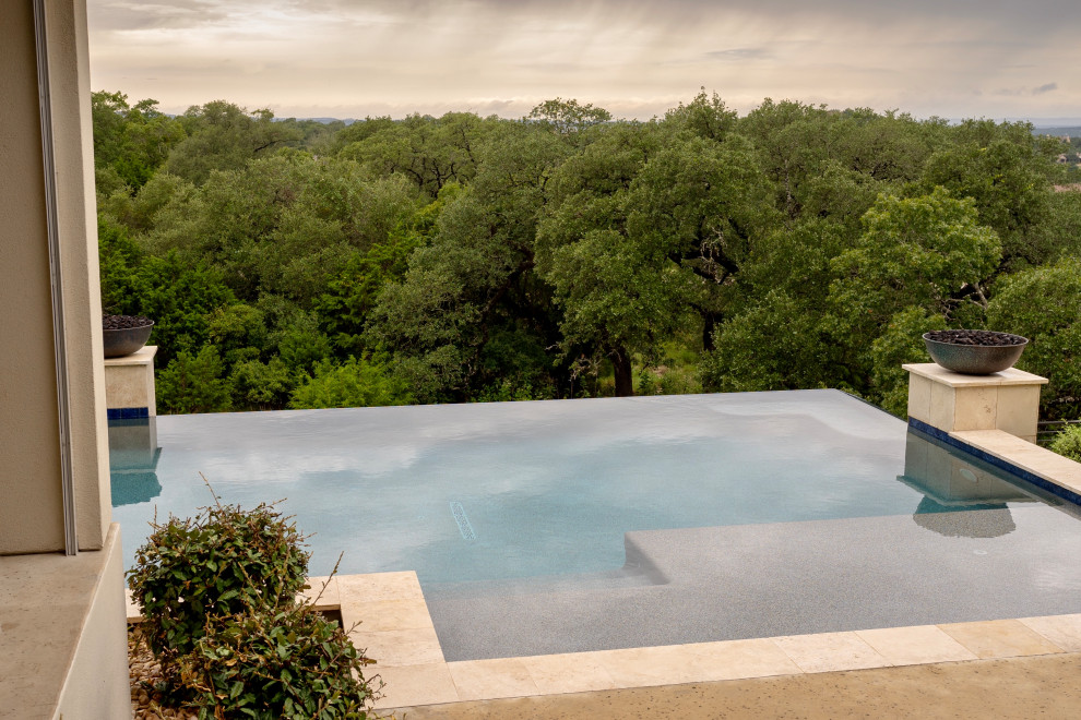 Photo of an expansive modern back private and rectangular infinity swimming pool in Austin with concrete slabs.