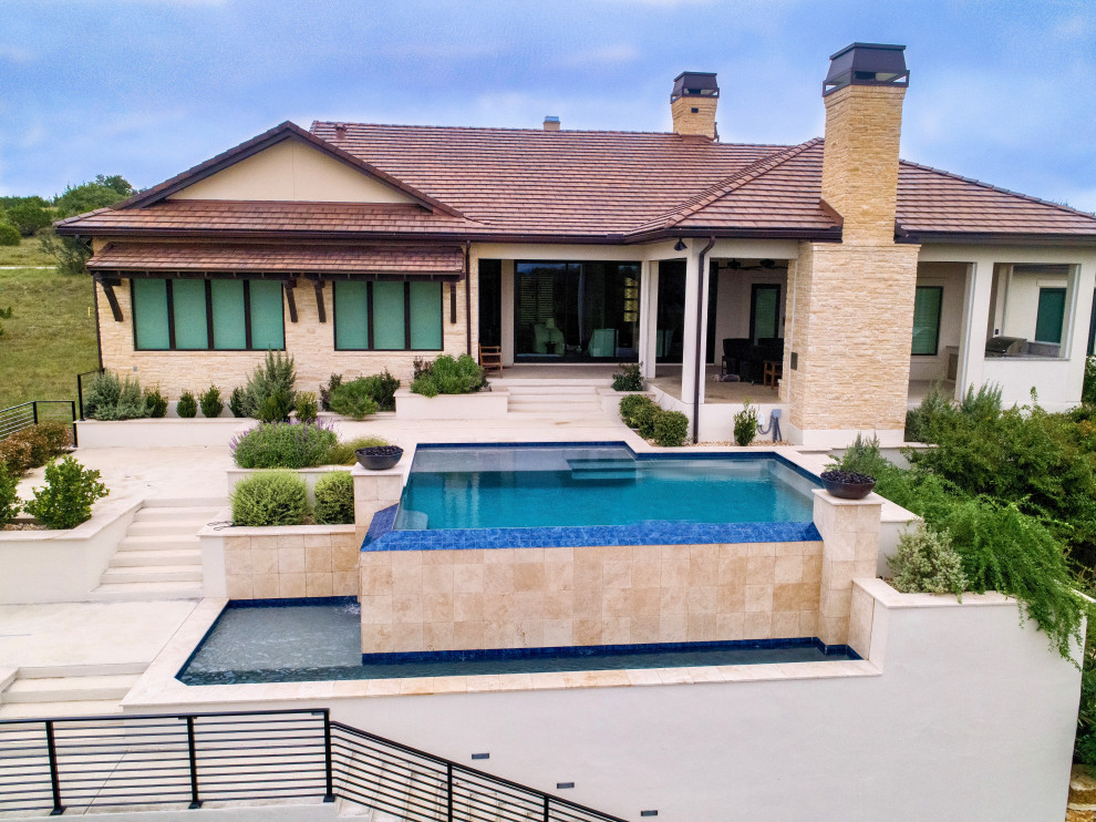 Foto di un'ampia piscina a sfioro infinito moderna rettangolare dietro casa con lastre di cemento