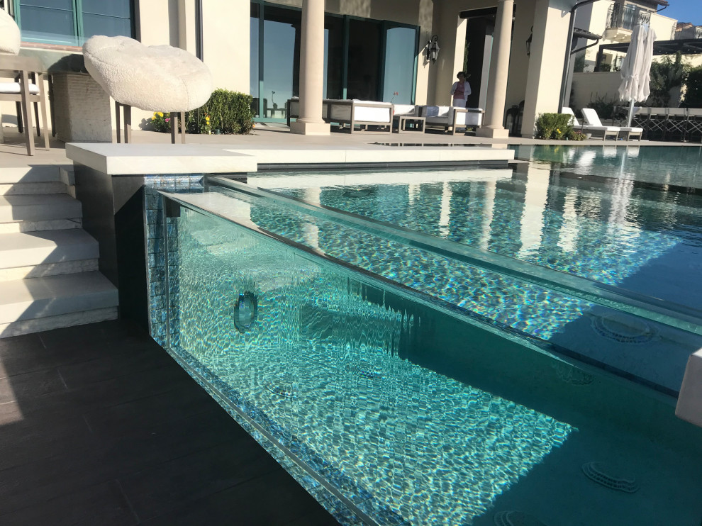 Idee per una grande piscina a sfioro infinito moderna personalizzata dietro casa con una vasca idromassaggio e piastrelle