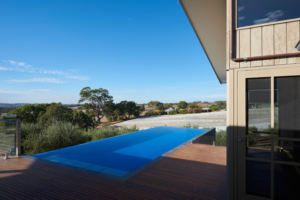 Ejemplo de piscina infinita contemporánea de tamaño medio rectangular en patio trasero con entablado