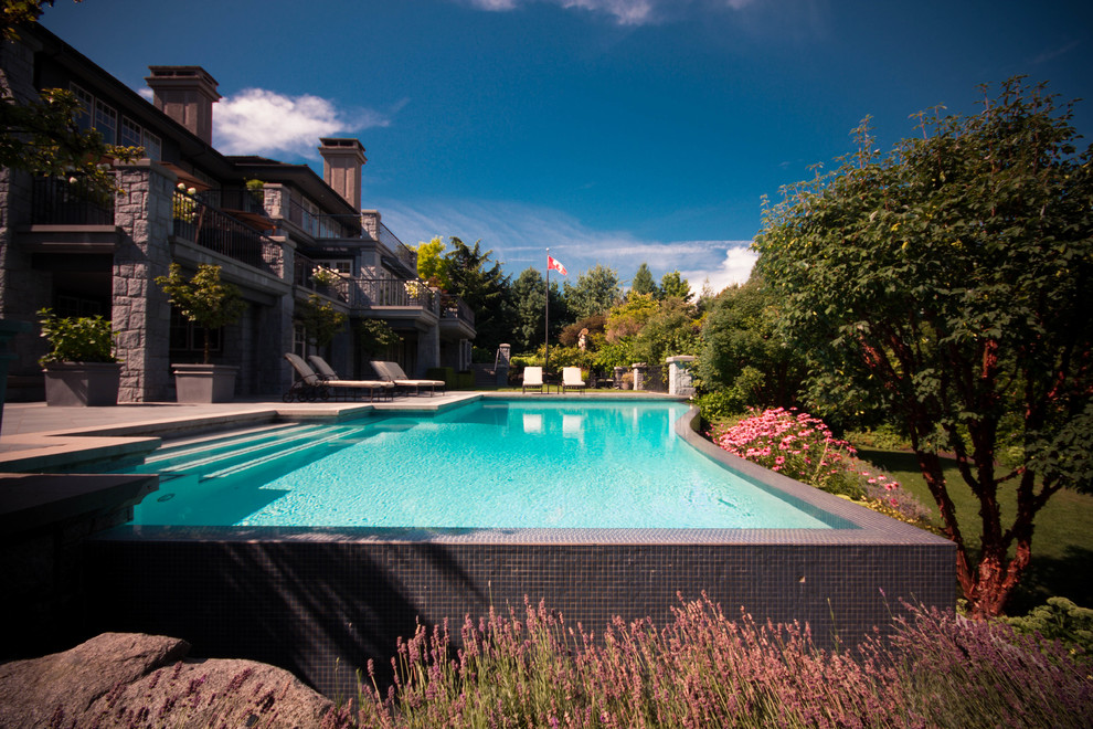 Ejemplo de casa de la piscina y piscina infinita clásica extra grande a medida en patio trasero con suelo de baldosas