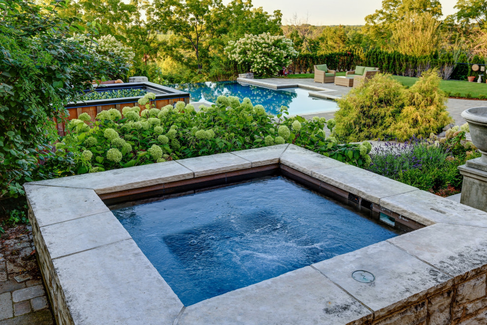 Foto di una piscina a sfioro infinito chic rettangolare di medie dimensioni e dietro casa con una vasca idromassaggio e pavimentazioni in cemento