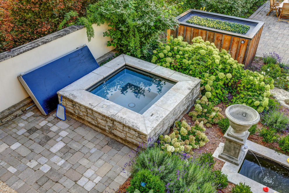 Aménagement d'une piscine à débordement et arrière classique de taille moyenne et rectangle avec un bain bouillonnant et des pavés en béton.