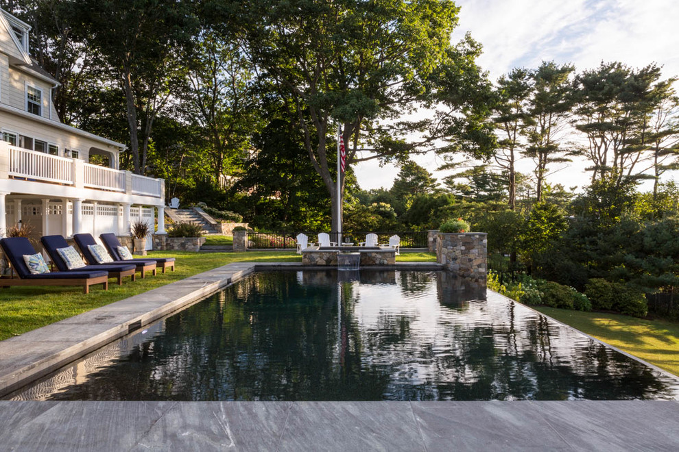 Immagine di una piscina a sfioro infinito chic rettangolare di medie dimensioni e dietro casa con una vasca idromassaggio e pavimentazioni in pietra naturale
