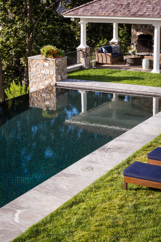 Modelo de piscinas y jacuzzis infinitos clásicos de tamaño medio rectangulares en patio trasero con adoquines de piedra natural