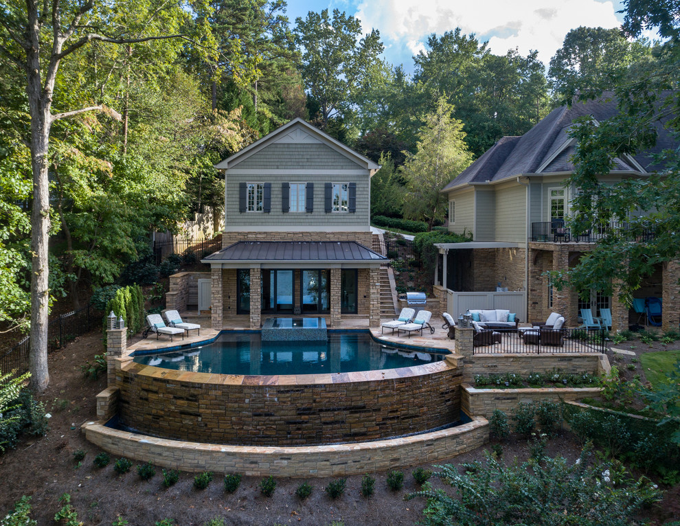 Immagine di un'ampia piscina a sfioro infinito chic personalizzata dietro casa con una dépendance a bordo piscina e pavimentazioni in mattoni