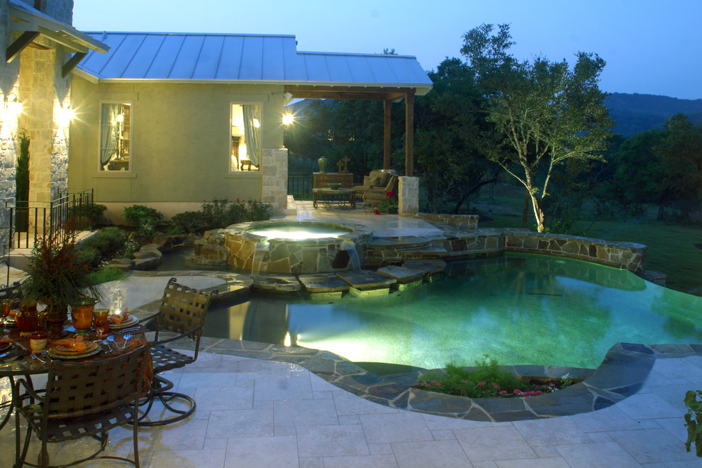 Cette photo montre une piscine à débordement et arrière chic de taille moyenne et sur mesure avec un bain bouillonnant et des pavés en pierre naturelle.