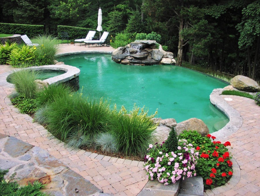Immagine di una grande piscina a sfioro infinito minimalista personalizzata dietro casa con una vasca idromassaggio e cemento stampato