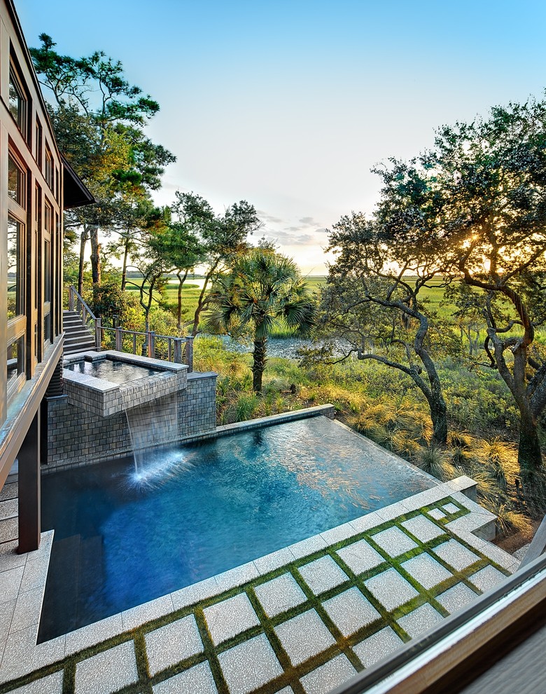 Modelo de piscina con fuente infinita minimalista de tamaño medio rectangular en patio trasero con adoquines de hormigón